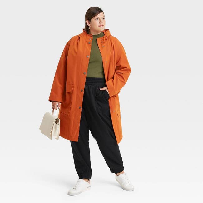 model in rust-tone mid-length rain jacket with rolled joggers and tee