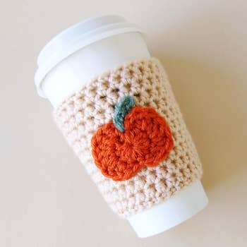 a knit coozy with a pumpkin in the middle