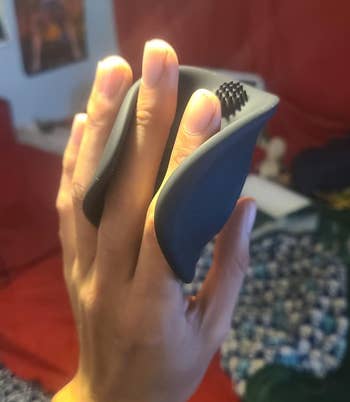 Hand holding a achromatic silicone vibrating stroker with a textured nub connected the wrong of the sleeve