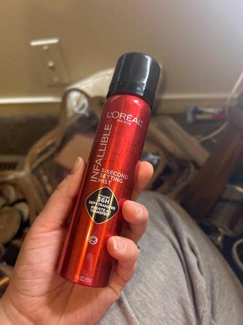 Hand holding L'Oreal Infallible Setting Mist aerosol with 