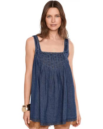 Person wearing a sleeveless denim formal with pleated details, posing for a buying article