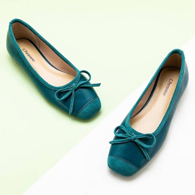 A pair of teal ballet flats with bows