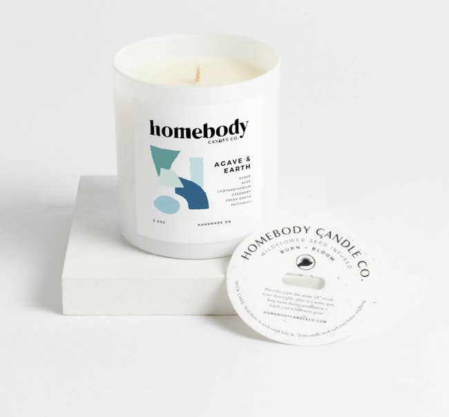 white candle with homebody logo on the front