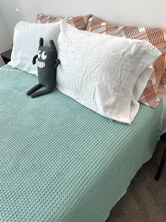 reviewer photo of the mint green waffle knit blanket on their bed