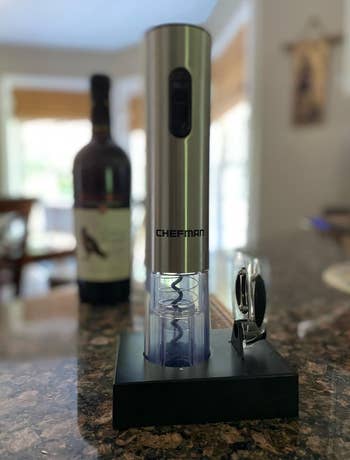 Electric wine opener on a kitchen counter with a bottle of wine in the background