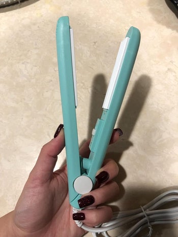  a reviewer holding the blue sealing tool that looks like a small hair straightener