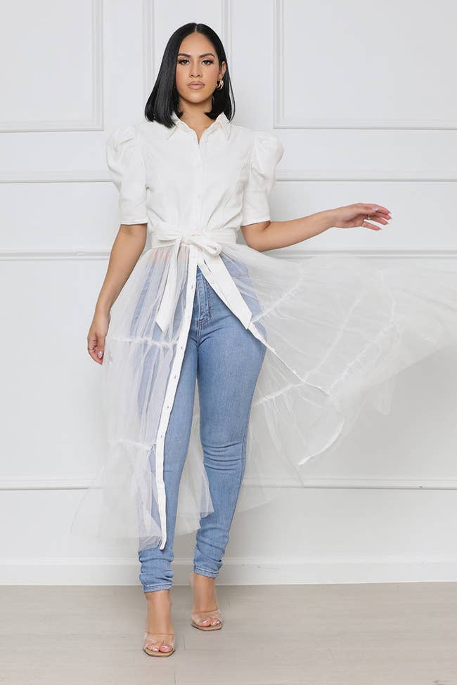 model in puff sleeve collared shirt with tie at waist and sheer tulle hanging down to the ankle
