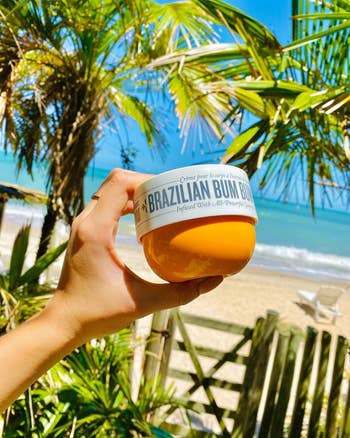 Model memegang toples krim gelandangan gelandangan Brasil di pengaturan pantai tropis