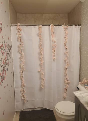 A bathroom with floral garlands on the shower curtain 