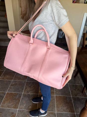 The same reviewer holding the pink duffle in 