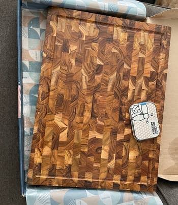 reviewer photo of the cutting board in its box, with a container of wax
