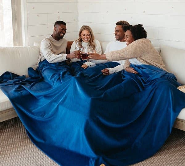 four model sitting under one blue blanket 