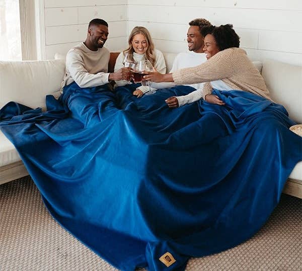 four model sitting under one blue blanket 