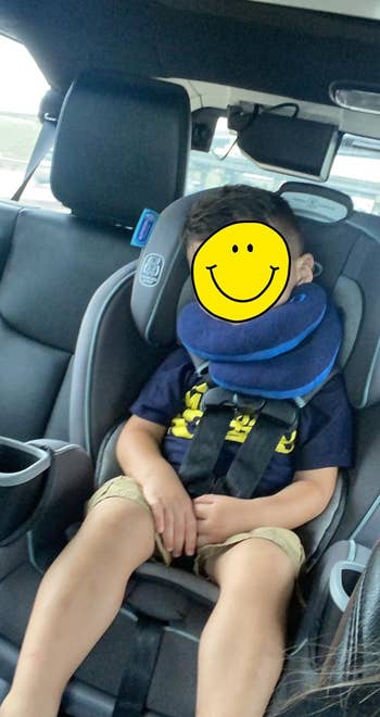 a reviewer photo of a child in a car seat using the pillow in blue 