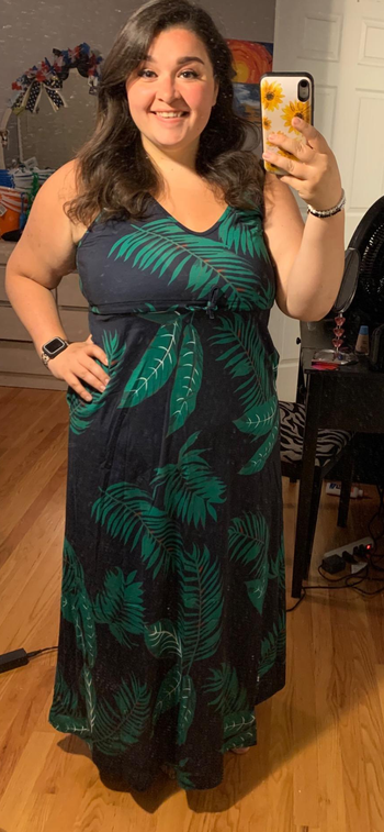 a reviewer wearing the dress in navy blue with a green palm print