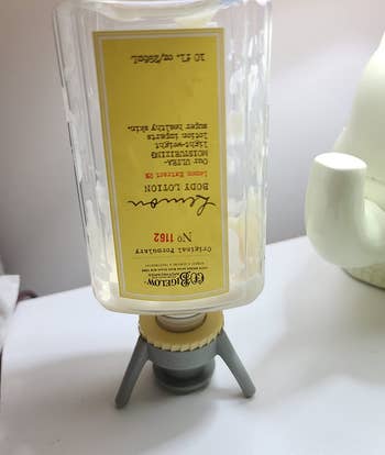 reviewer photo of the gray bottle emptying can propping up an upside down body lotion bottle