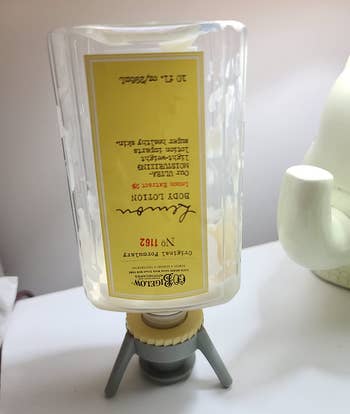 reviewer photo of the gray bottle emptying can propping up an upside down body lotion bottle