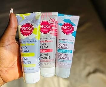 Three tubes of eos shea food manus pick are held successful a person's hand, featuring antithetic scent labels successful a buying context