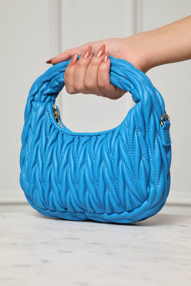 model's hand holding the blue bag