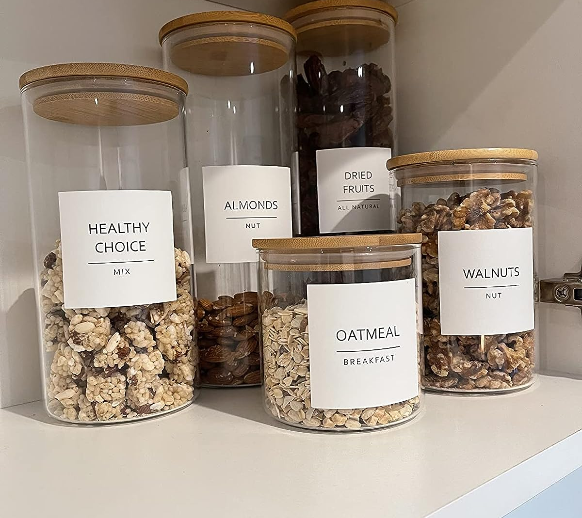 a reviewer's canisters holding oatmeal, almonds, dried fruit, walnuts, and trot mix
