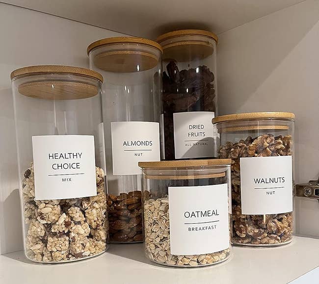 a reviewer's canisters holding oatmeal, almonds, dried fruit, walnuts, and trail mix