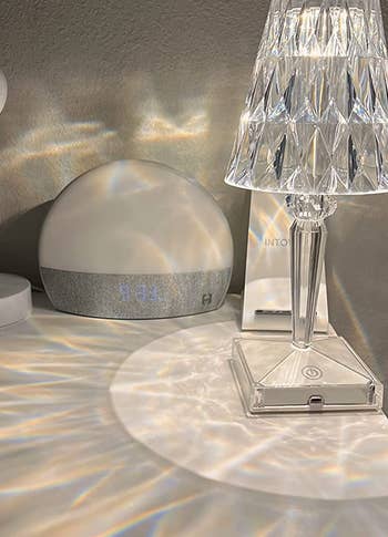 a little crystal table lamp turned on, casting prisms of light on the table