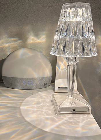 a reviewer's little crystal table lamp turned on, casting prisms of light on the table