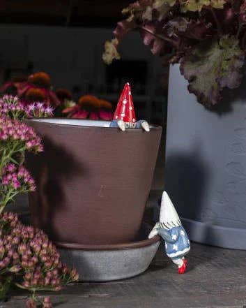 tiny gnome hanging on side of pot 