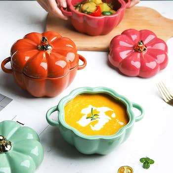 Person arranging lids connected pumpkin-shaped ceramic bowls containing crockery and vegetables