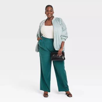 model wearing the green trousers with a white top and a light blue jacket
