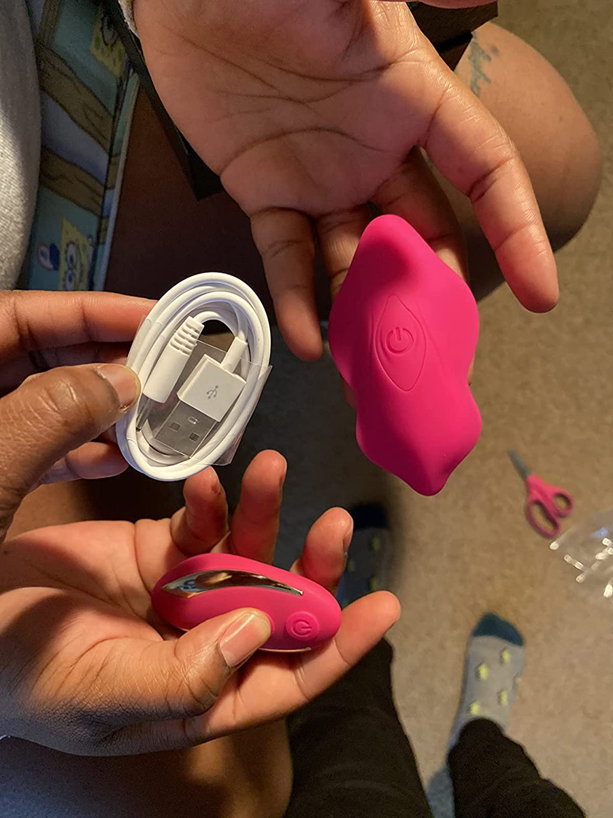 Reviewers holding pink butterfly panty vibrator, wireless remote and charging cord
