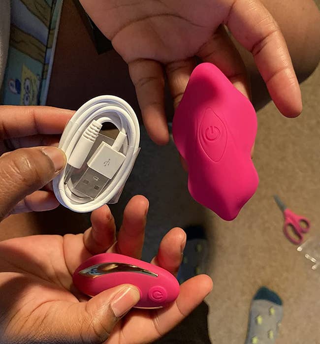 Reviewers holding pink butterfly panty vibrator, wireless remote and charging cord