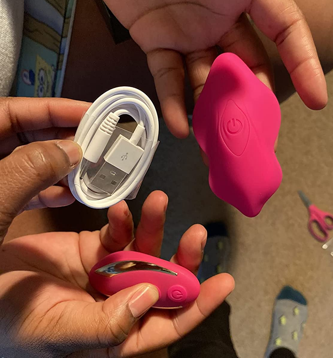 Reviewers holding pink butterfly panty vibrator, wireless remote and charging cord