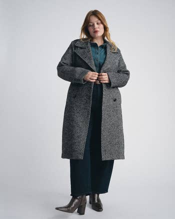 Person wearing a stylish agelong overgarment implicit a blouse and jeans, paired with ankle boots. Suitable for a buying article
