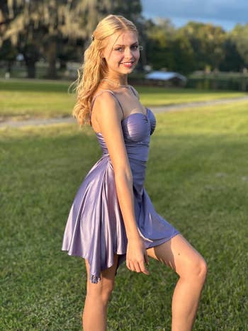 Person outdoors successful  a satin formal  with a flared skirt, posing connected  a grassy tract  with trees successful  the background