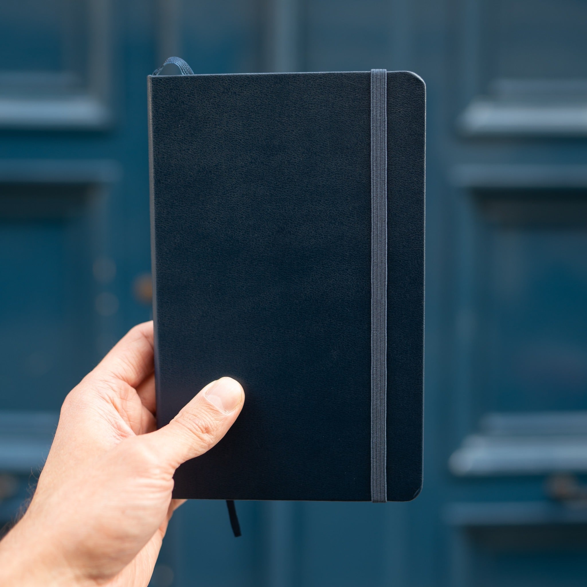 person holding moleskine notebook