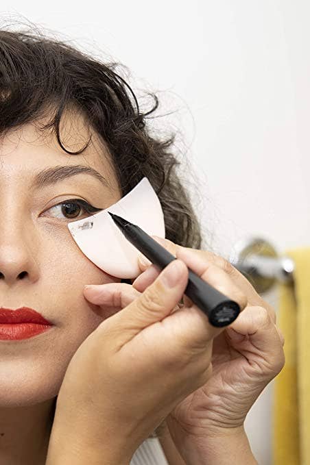 a exemplary holding the silicone shield nether their oculus portion applying eyeliner