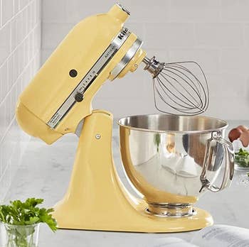the yellow stand mixer on a counter with its head tilted back