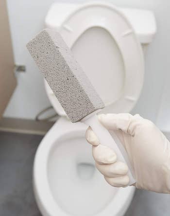 the pumice stone held in front of a toilet