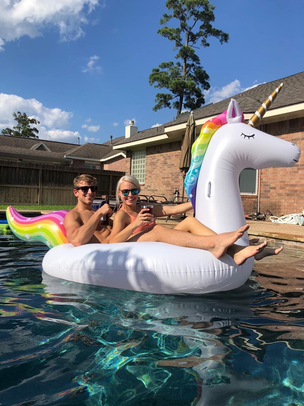 two reviewers sitting on the large unicorn with rainbow mane and tail