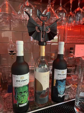 Three themed wine bottles with character illustrations displayed on a bar shelf