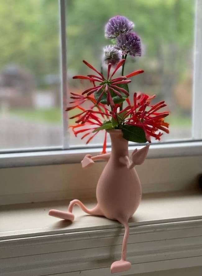 reviewer photo of the pink vase on a window sill and one leg bent up on the sill