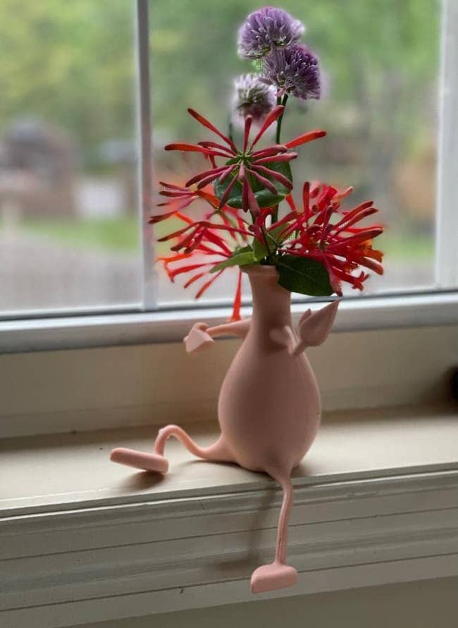 reviewer photo of the pink vase on a window sill and one leg bent up on the sill