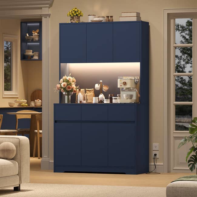 Modern kitchen nook with blue cabinets, coffee maker, and flowers on the counter. Elegant and organized setup for home dining space
