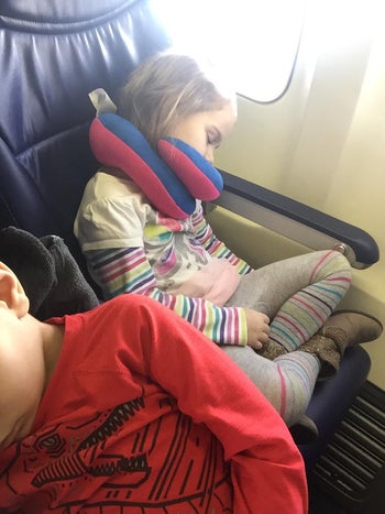 hotel customer picture of a kid sleeping on an aircraft with the neck pillow on