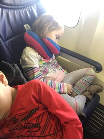 reviewer image of a child sleeping on a plane with the neck pillow on