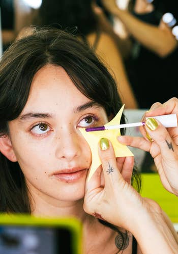 a make up artist using the tool to apply clean mascara