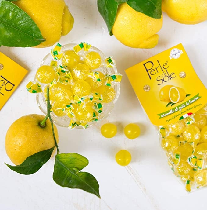 a package of Perle di Sole Lemon Drops with loose candies in a dish and on a table