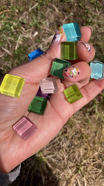 Hand holding various translucent square magnets