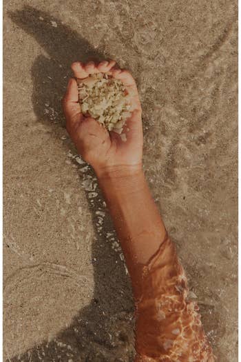 Hand holding grains of soil successful wide h2o connected a sandy beach